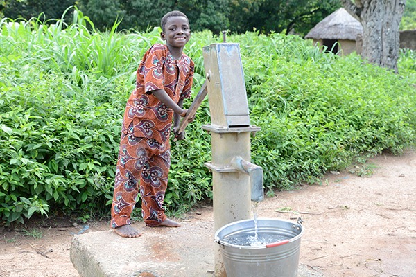 In Nigeria, Danjuma pumps clean fresh water from a borehole.]