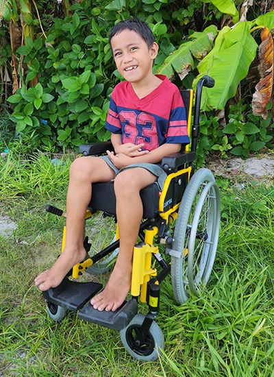 In Tuvalu Enoch, with cerebral palsy and down syndrome, received a new wheelchair buggy to help transport him around his island home.]