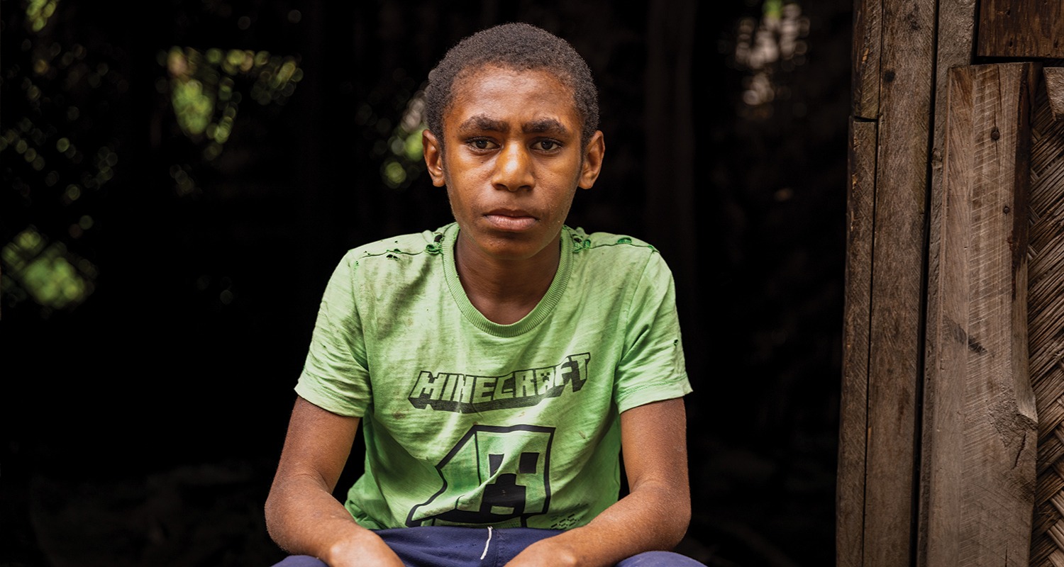 Patrick sitting outside his home in in Papua New Guinea, waiting for sight-saving cataract surgery