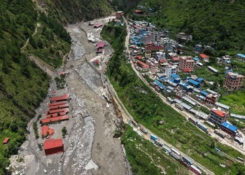 An aerial view of a Nepali town cut off by a flood-scoured river valley.