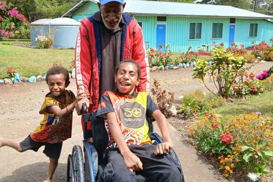 Enoch, age four, sitting in his specialised wheelchair buggy in Tuvalu and looking at the camera