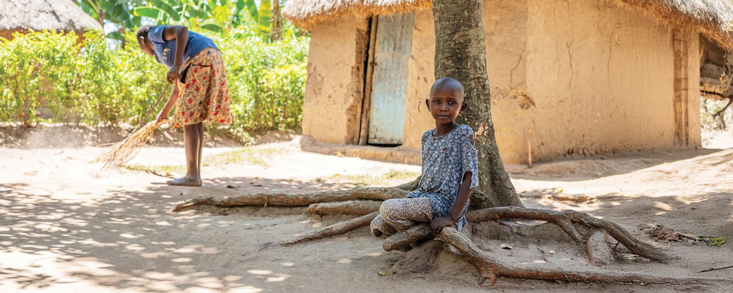 Faith sitting alone outside her home in rural Uganda, waiting for sight-saving cataract surgery